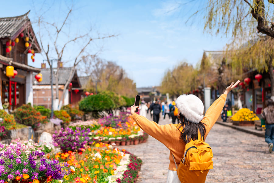 Turista con mochila disfrutando de un paseo por un pueblo tradicional en Yunnan, China.